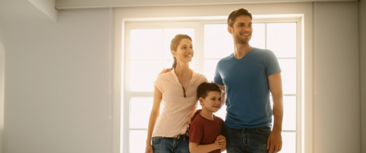 Una felice famiglia caucasica sorride in una stanza luminosa della loro nuova casa, simboleggiando un trasloco di successo e un nuovo inizio.